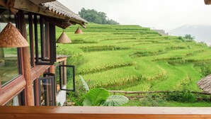 Vista desde un balcón de madera con vistas a campos de arroz en terrazas.