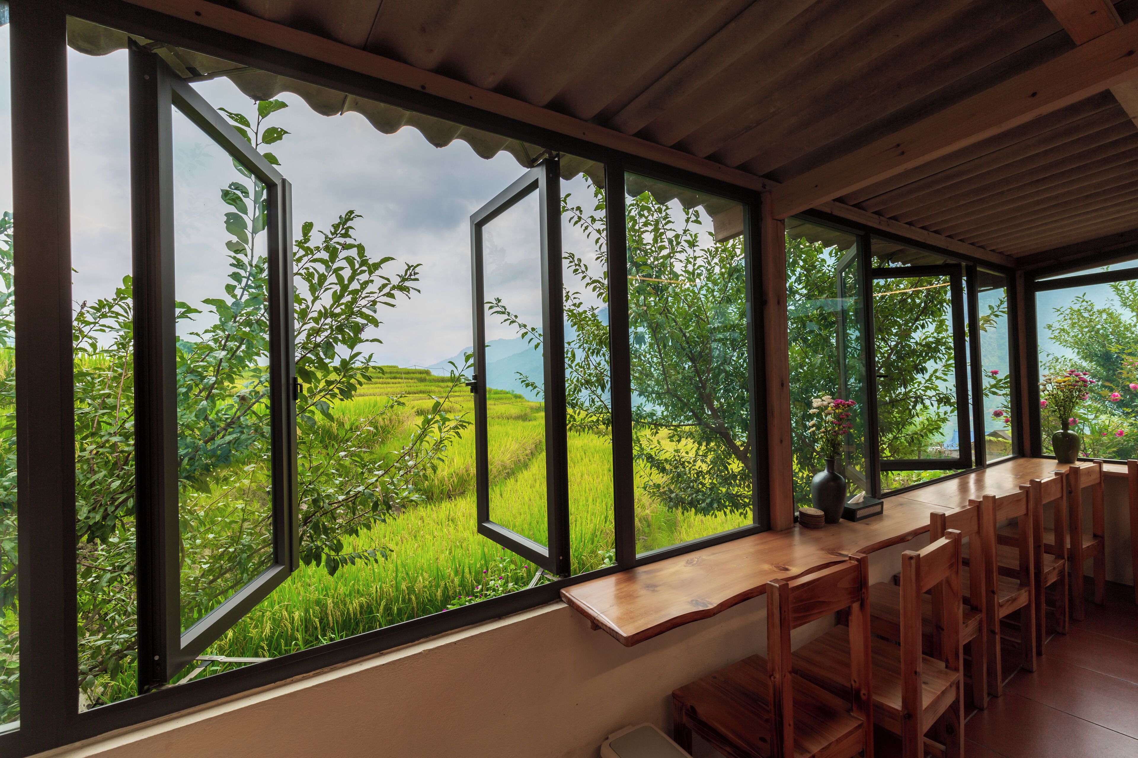 A dining area with a view of green fields and trees through large windows.