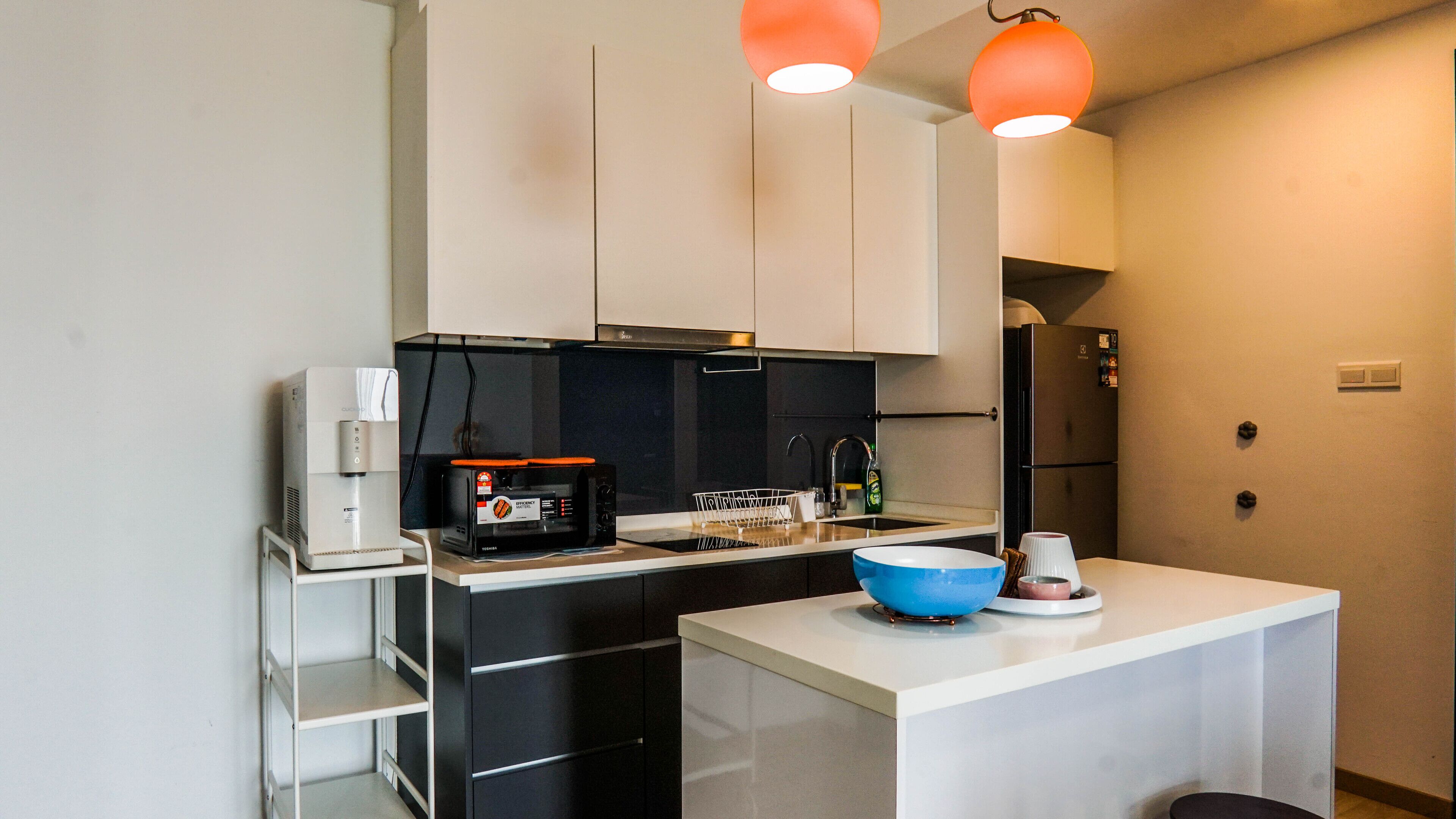 A compact kitchen with a coffee machine, microwave, and a small sink.