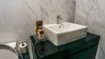 A bathroom with a white sink, a mirror, and toiletries on a shelf.