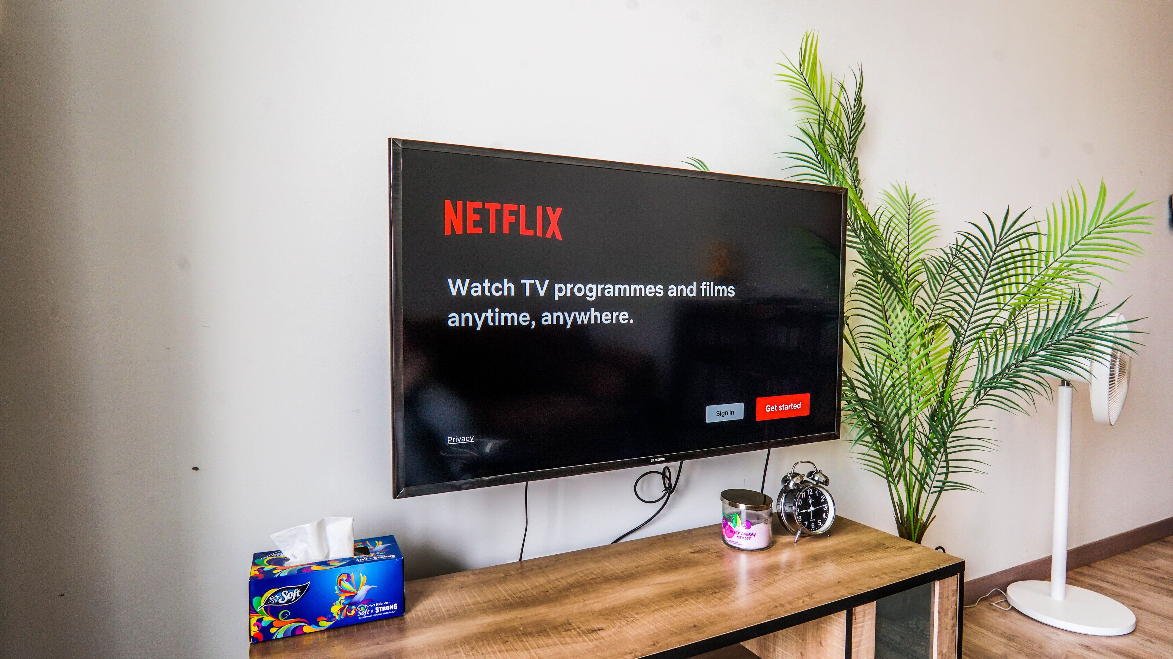 A flat-screen TV mounted on a wall displaying a Netflix welcome screen.