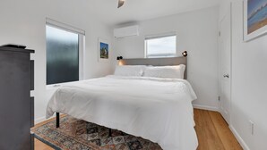 Une chambre à coucher avec un lit, un ventilateur de plafond, une fenêtre et une porte.