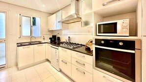 Una cocina moderna con armarios blancos, estufa a gas, microondas y horno.