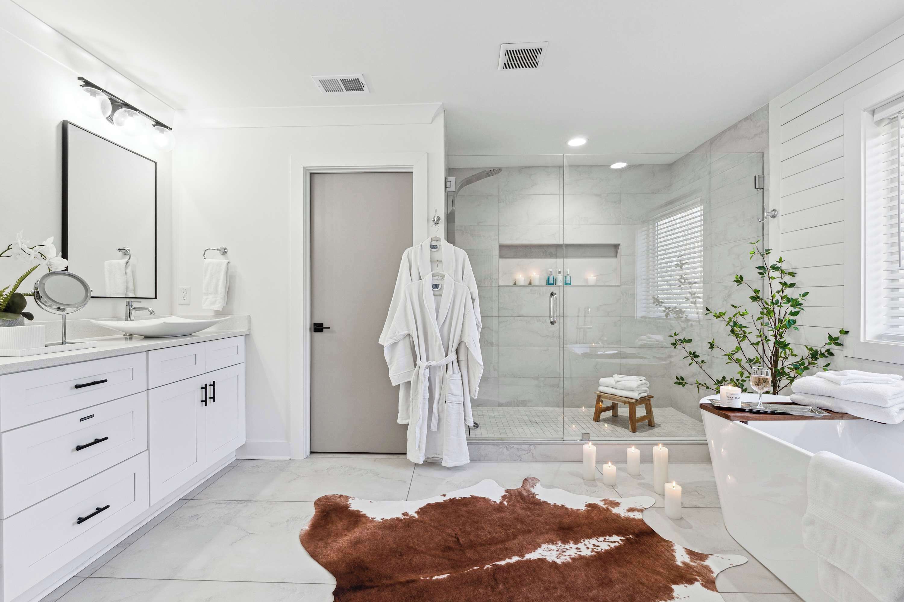 Une salle de bain moderne avec une douche en verre, des meubles blancs et un grand miroir.