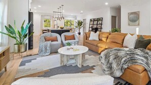 A modern living room with a sofa, armchairs, a coffee table, and a dining area.