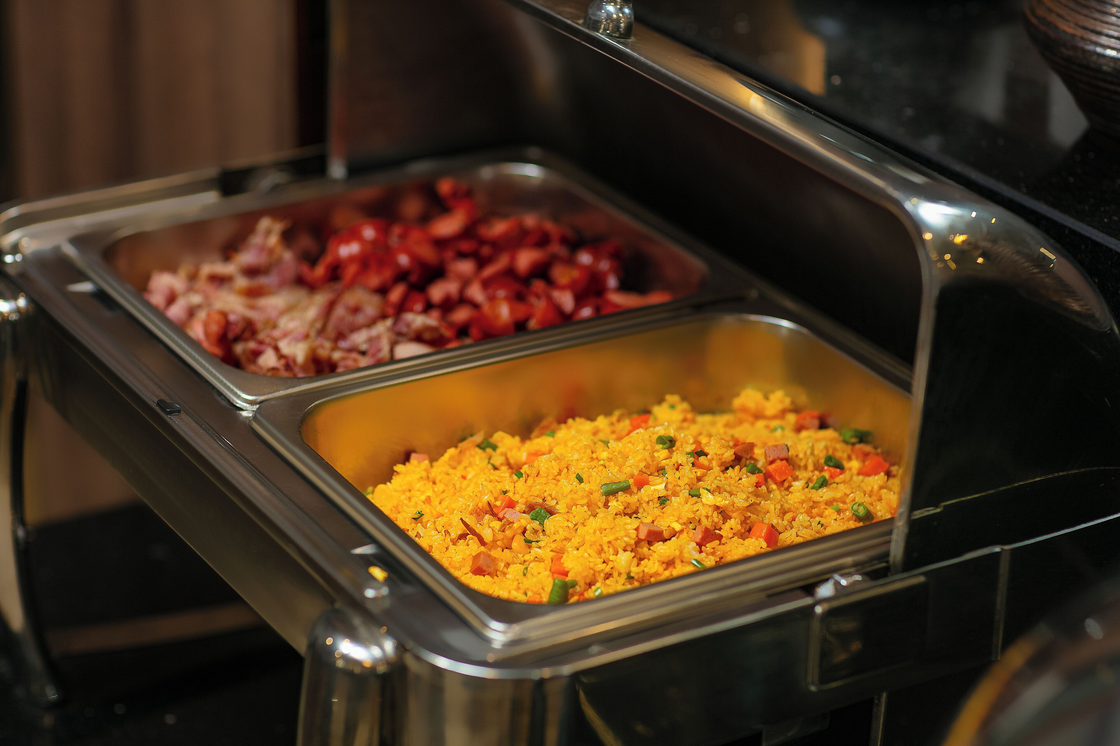 A buffet with two trays of food, one with red meat and the other with rice and vegetables.
