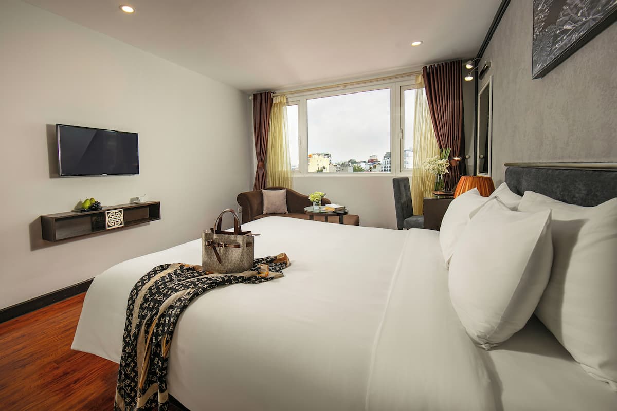 A hotel room with a large bed, a TV, a small table, and a chair.