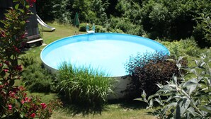 Una piscina rodeada de exuberante vegetación y un tobogán.