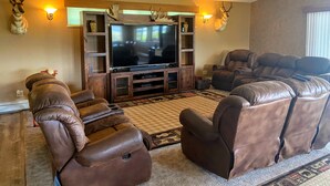 A living room with a large flat-screen TV, leather recliners, and wall-mounted deer antlers. - FUN FAMILY GETAWAY in Manila with lots of extras!  (Manila)