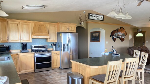 A modern kitchen with wooden cabinets, stainless steel appliances, and a central island with chairs. - FUN FAMILY GETAWAY in Manila with lots of extras!  (Manila)