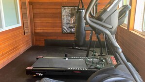A gym with treadmills and an elliptical machine, wooden walls, and a motivational poster. - FUN FAMILY GETAWAY in Manila with lots of extras!  (Manila)