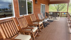 A wooden deck with four wooden chairs and a table, overlooking a grassy area. - FUN FAMILY GETAWAY in Manila with lots of extras!  (Manila)