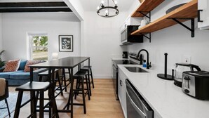 Uma cozinha moderna com ilha central, banquetas, forno embutido e máquina de lavar louça.
