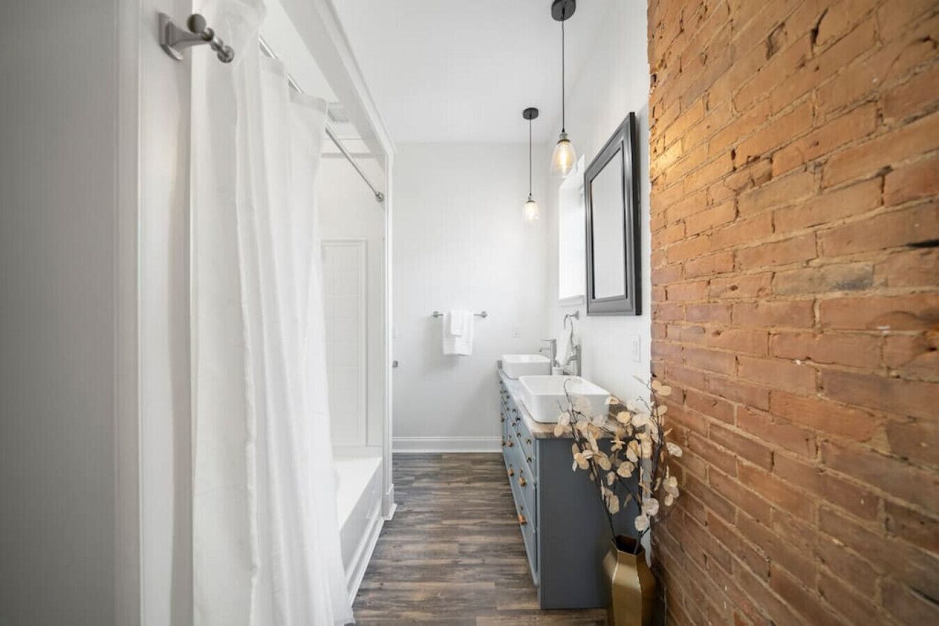 Un couloir étroit mène à une salle de bain avec une porte blanche, un lavabo et un miroir au mur.