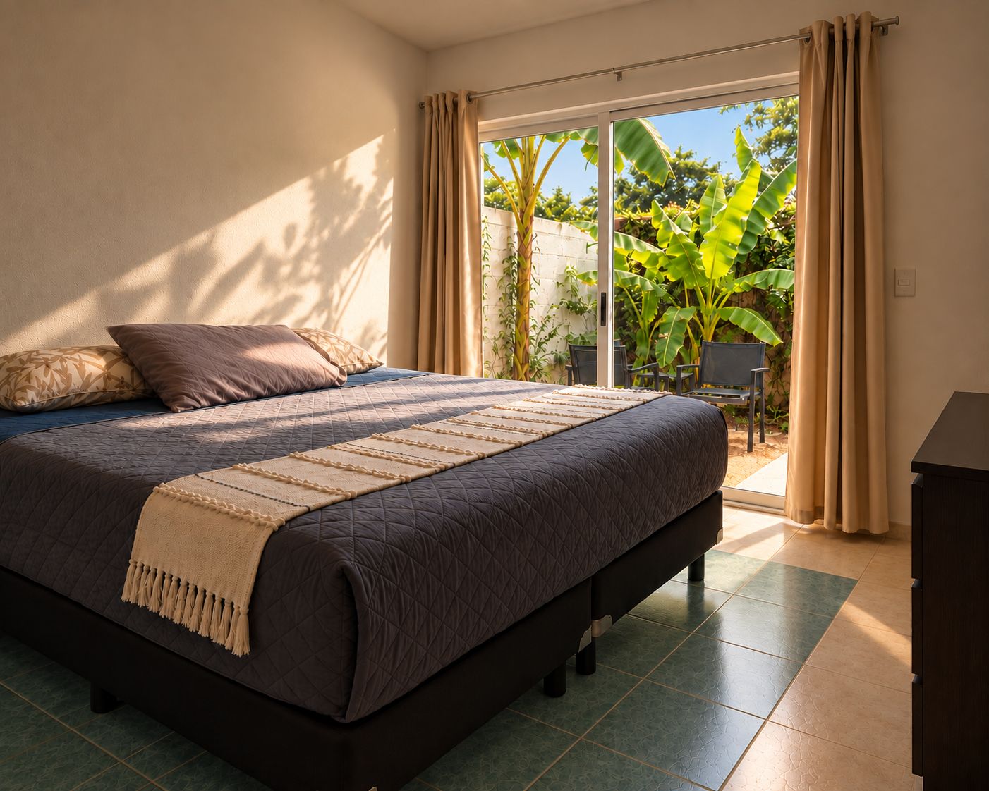 A bedroom with a large bed, a view of a garden through a sliding door, and a chair outside.