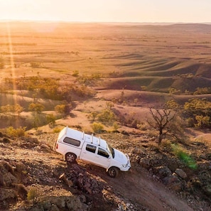 A white pickup truck parked on a rocky terrain with a vast landscape in the background.