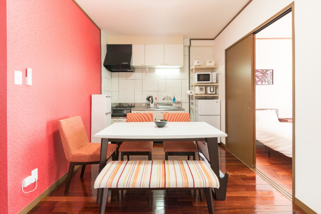 Cocina compacta con gabinetes blancos, microondas y una campana extractora negra.