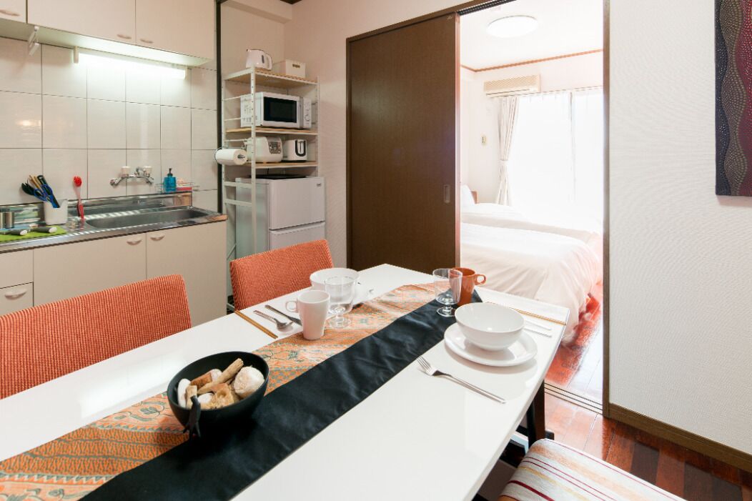 Habitación de hotel con comedor, kitchenette y una cama.