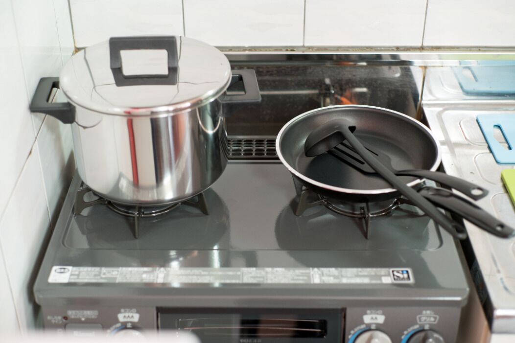 Une cuisine avec un fourneau, une casserole sur le brûleur de gauche et une poêle sur le brûleur de droite.