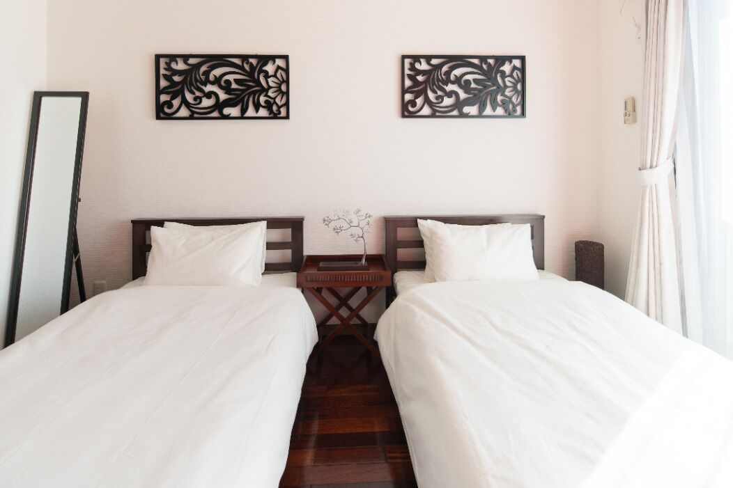 Habitación de hotel con dos camas individuales, una mesita de noche de madera y dos paneles decorativos en la pared.