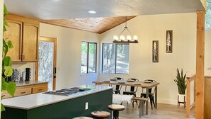 Una cucina moderna con isola centrale, sgabelli da bar, pensili in legno e un'ampia finestra che fa entrare luce naturale.