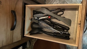 A drawer containing kitchen utensils including whisks, a grater, and a knife. - 19FT RAPTOR RV (Wasilla)