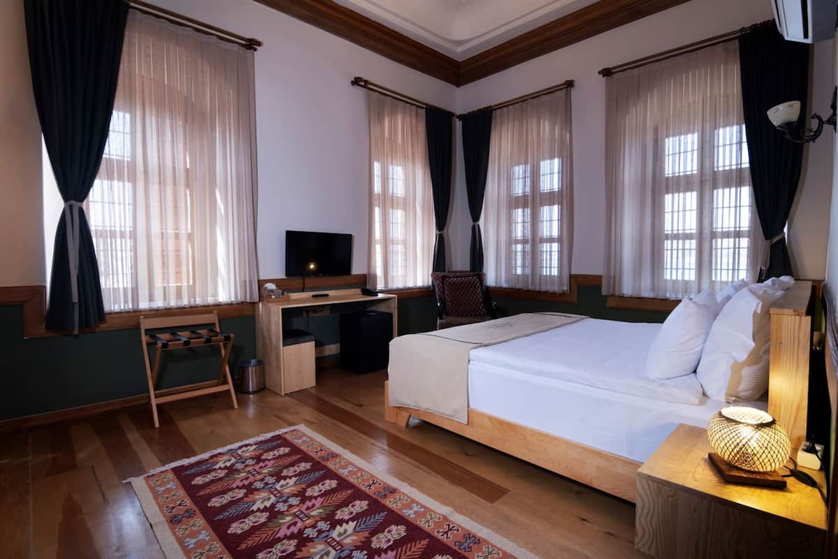 Un dormitorio con cama, escritorio, silla, televisor y una lámpara decorativa.