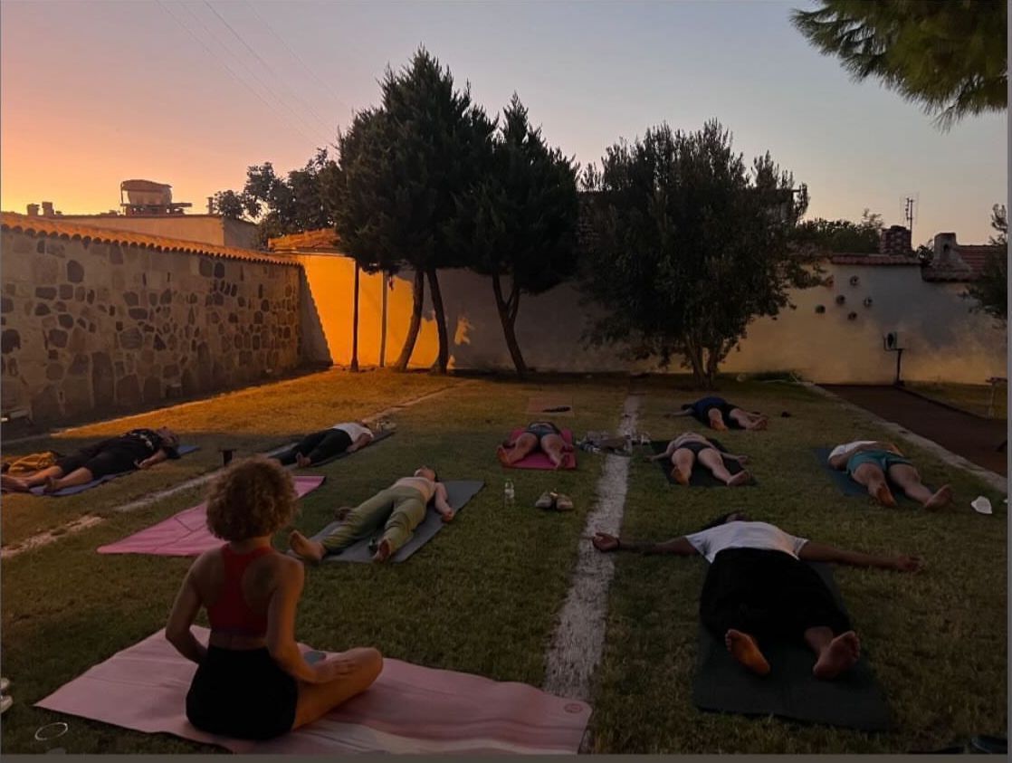 A group of people lying on mats outdoors during sunset.