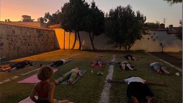 A group of people lying on mats outdoors during sunset.