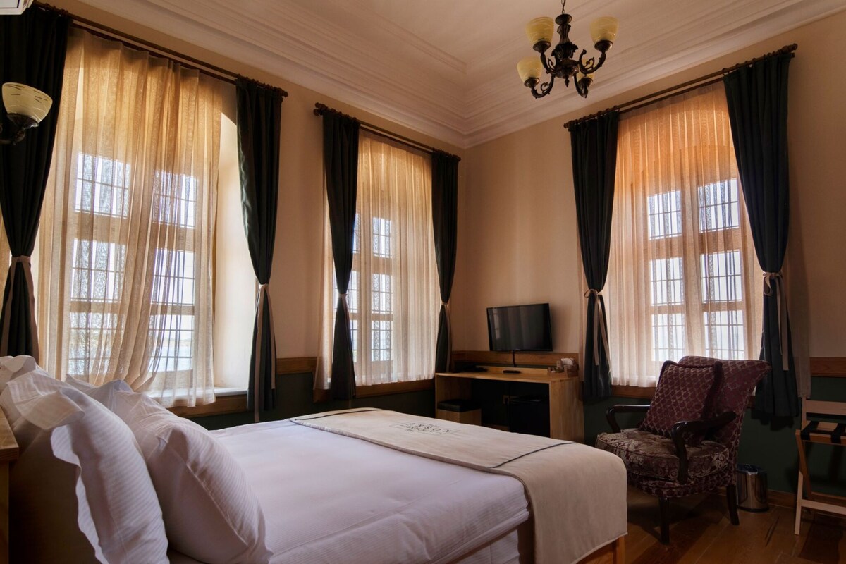 Una habitación de hotel con una cama, un escritorio, una silla y un televisor.