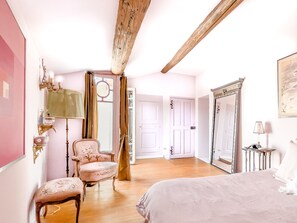 Classic design features a large bed, vintage chair, and ornate mirror.