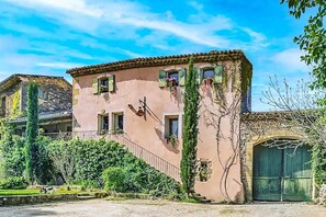 Traditional Mediterranean-style building with a central entrance and lush green surroundings.
