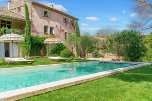 Relax by the serene pool surrounded by lush greenery and comfortable lounge chairs.