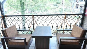 A balcony with two cushioned chairs and a small table, surrounded by a decorative metal fence with orange garlands. - Akansha The Lake View (Nainital)