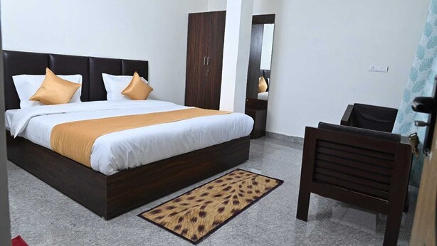 A hotel room with a large bed, a wooden wardrobe, a desk, and a chair. - Akansha The Lake View (Nainital)