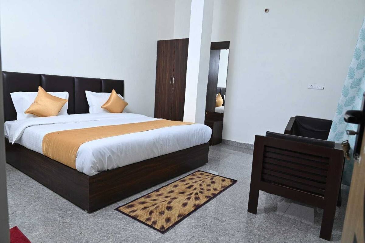 Quarto de hotel com uma cama grande, um guarda-roupa de madeira, uma escrivaninha e uma cadeira.
