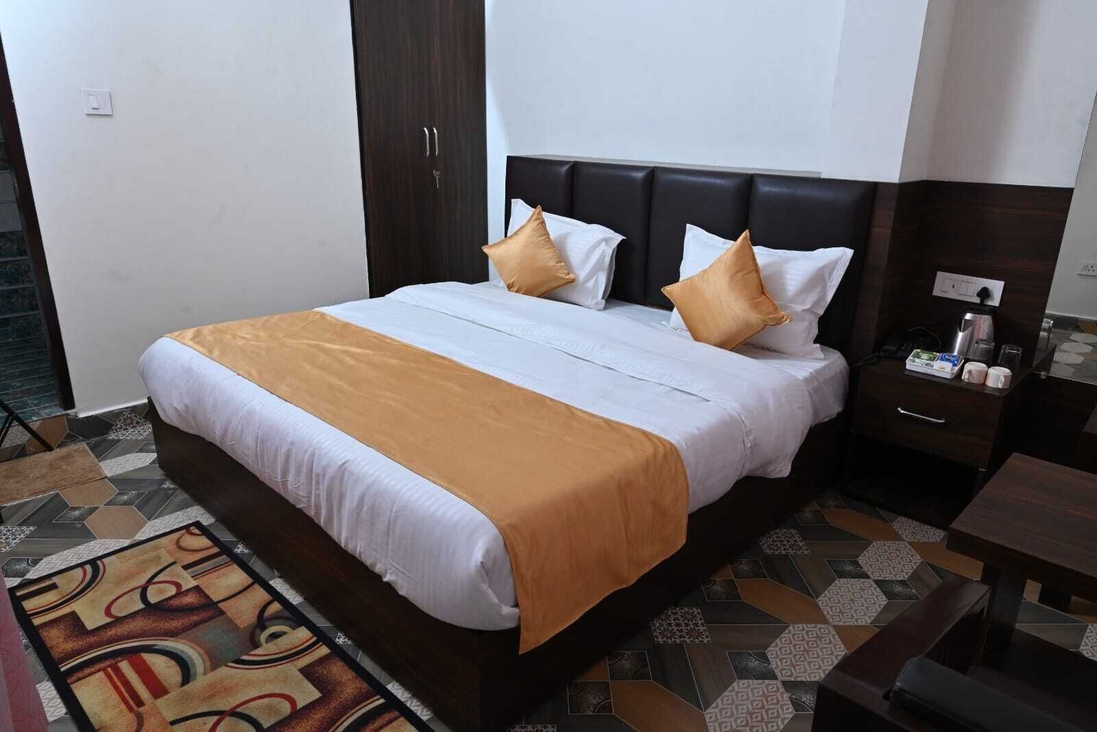 A neatly made bed with a white and orange bedspread, two pillows, and a dark headboard.