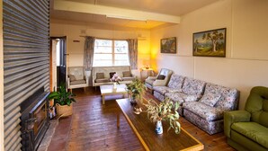Un salon comprenant un canapé, un divan à motifs floraux, une table basse en bois et une cheminée.