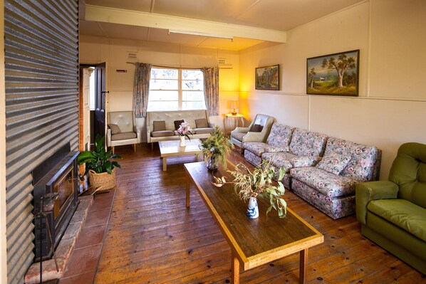 A living room with a sofa, a floral-patterned couch, a wooden coffee table, and a fireplace.