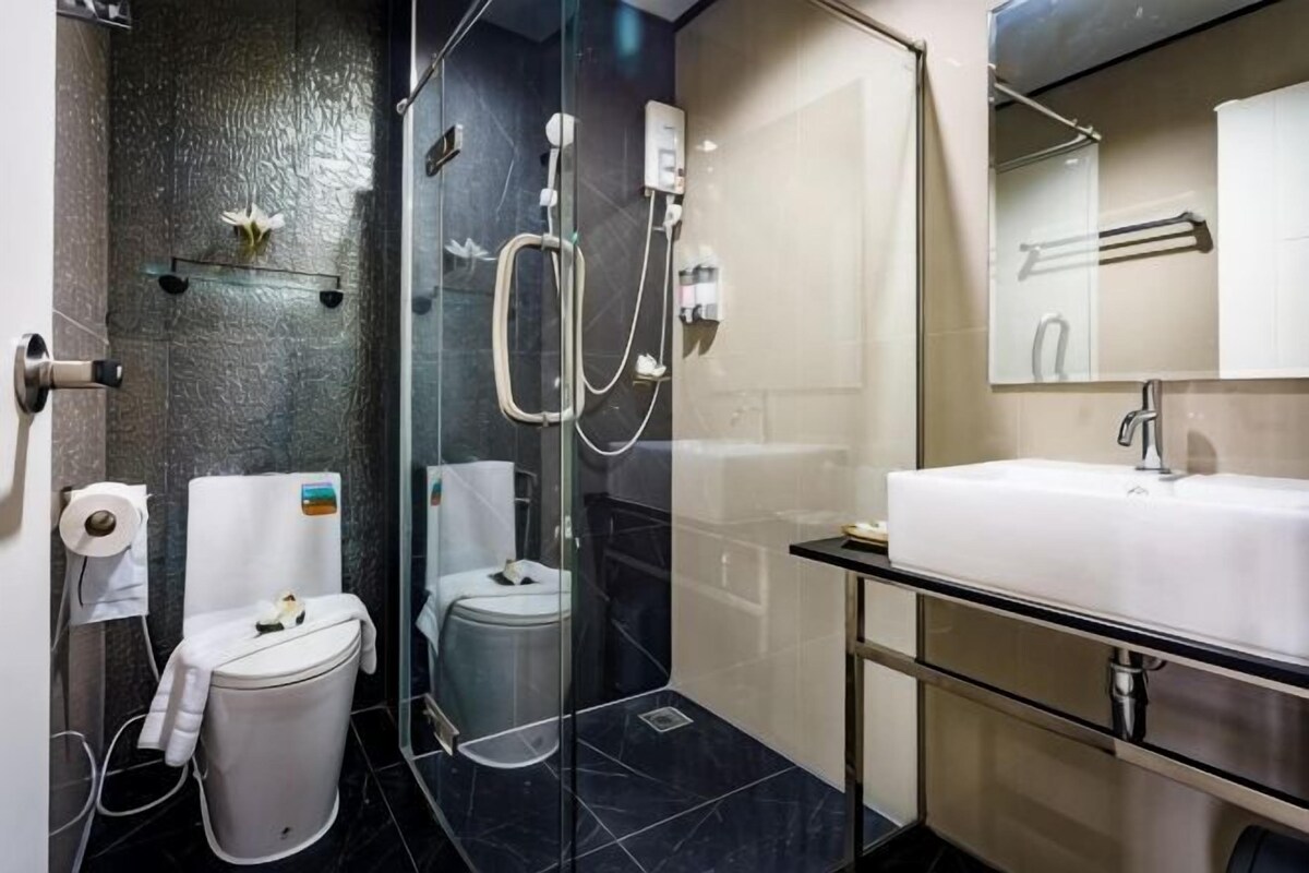 A modern bathroom with a glass-enclosed shower, a white sink, and a toilet.
