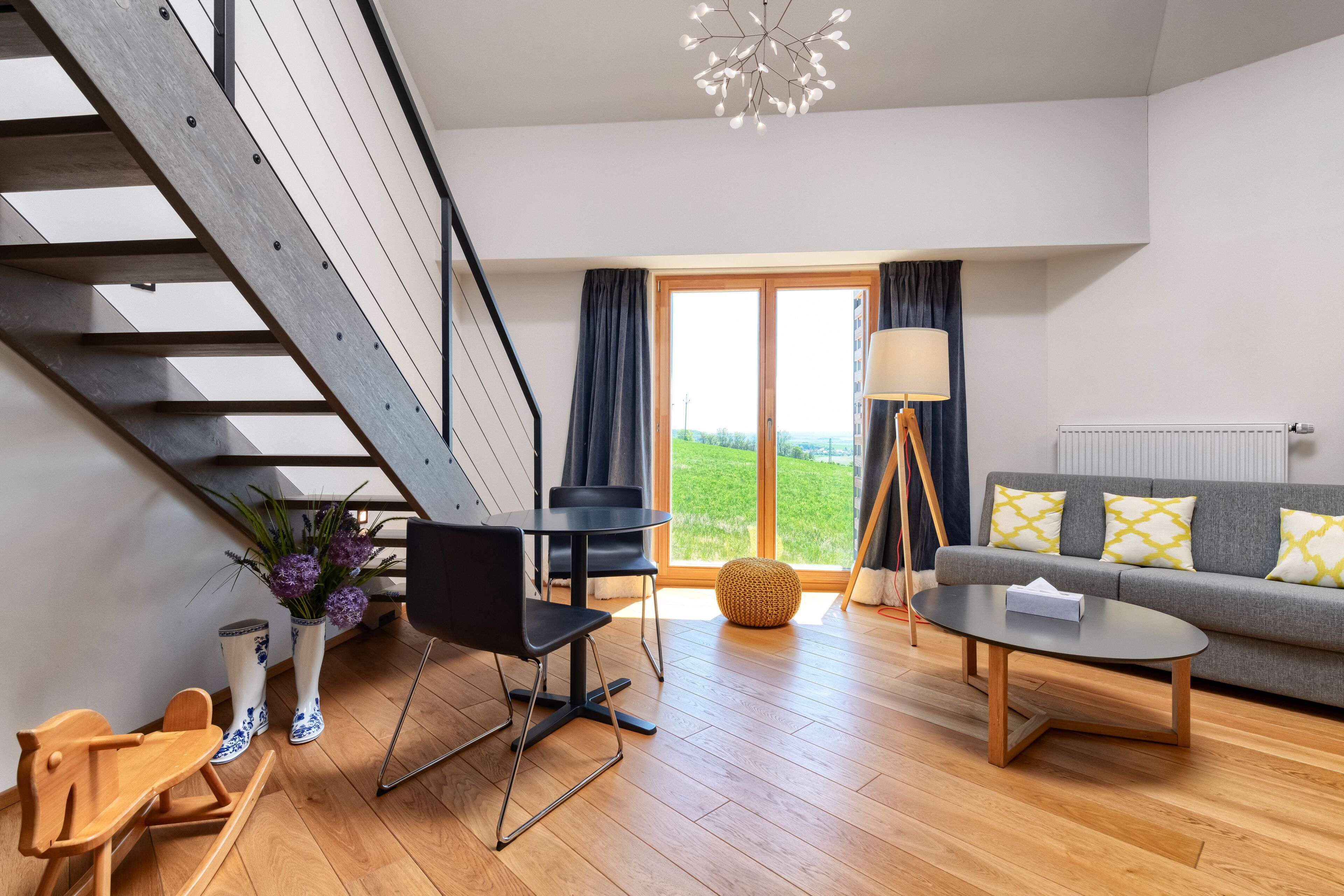 A modern living room with a staircase, a sofa, a coffee table, and a dining area.