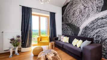 A modern living room with a large window, a dark-colored sofa, a wooden coffee table, and a yellow armchair.