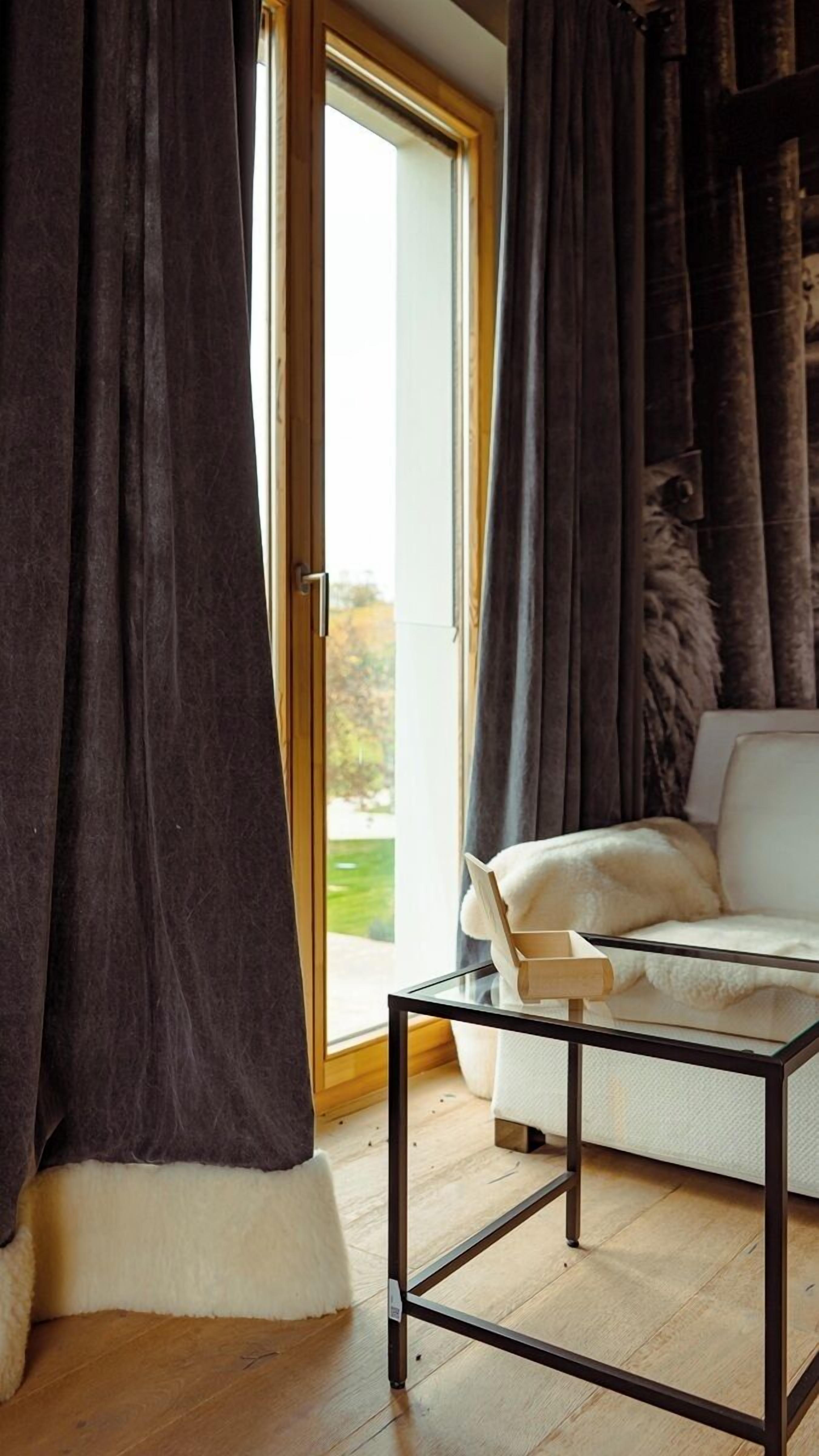 A room with a glass door leading to a balcony, a white sofa, and a glass coffee table.