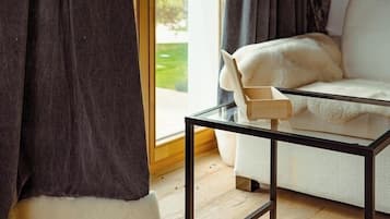 A room with a glass door leading to a balcony, a white sofa, and a glass coffee table.