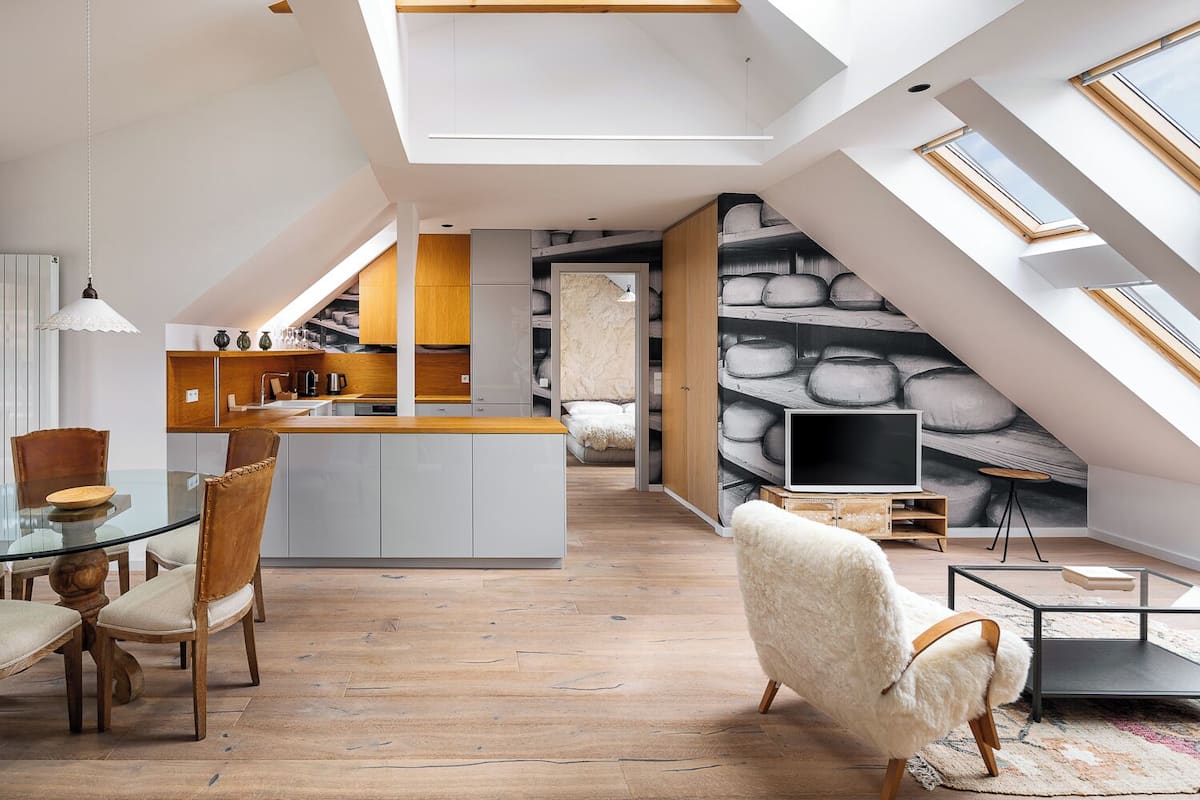 Un loft moderno con techos altos, tragaluces, una isla de cocina central y una zona de estar acogedora con televisión.