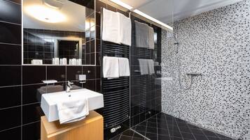 A modern bathroom with a black tiled wall, a white sink, and a mirror.