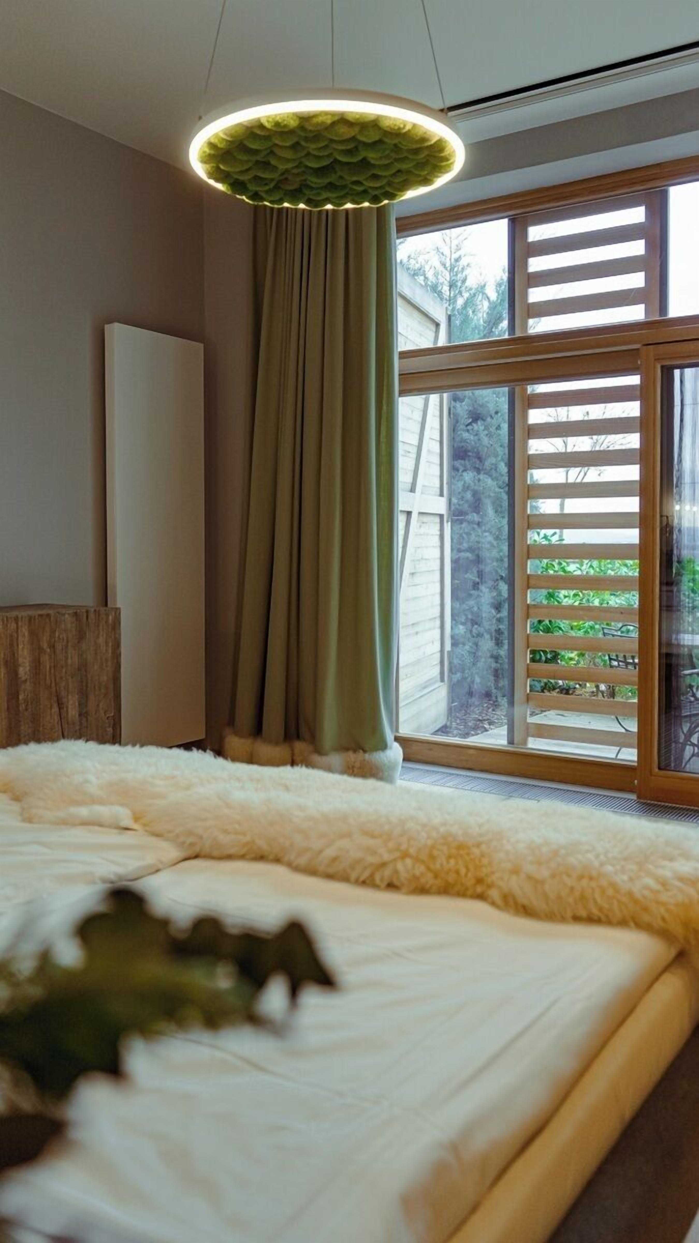 A bedroom with a large bed, a green curtain, and a window with blinds.