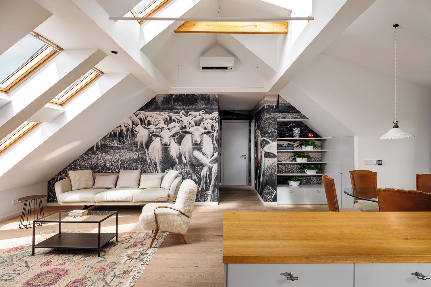 Un loft moderne doté de fenêtres de toit, d’une fresque murale, d’un coin repas et d’un espace salon confortable.