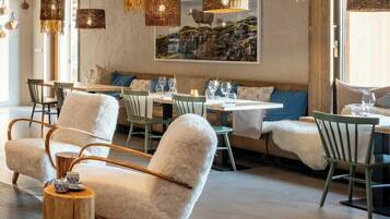 Un interior de restaurante moderno con lámparas colgantes de mimbre, asientos acolchados y una pared de piedra con un cuadro.