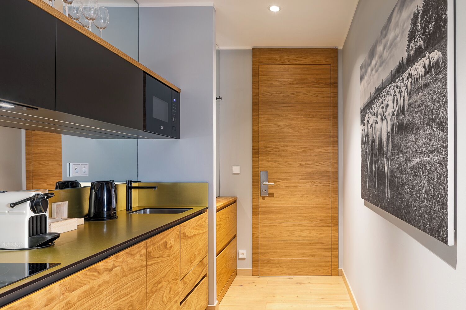 A modern kitchen with a wooden countertop, black cabinets, and a black coffee machine.